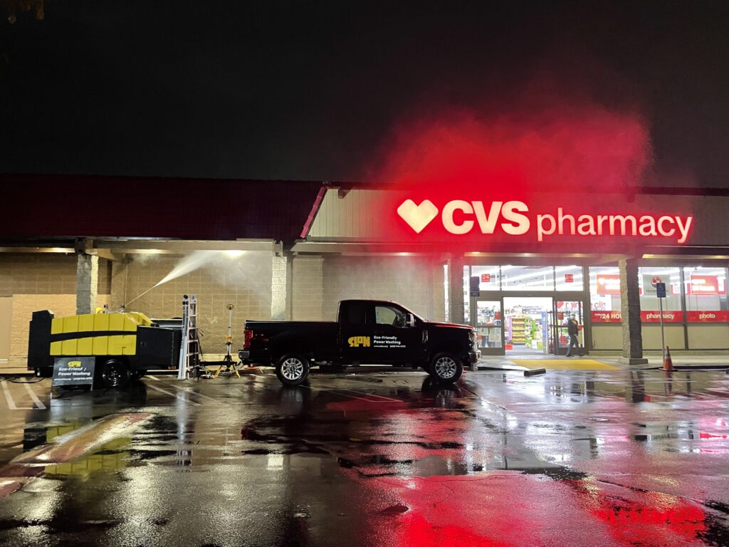 Pressure washing trailer in front of CVS at night.