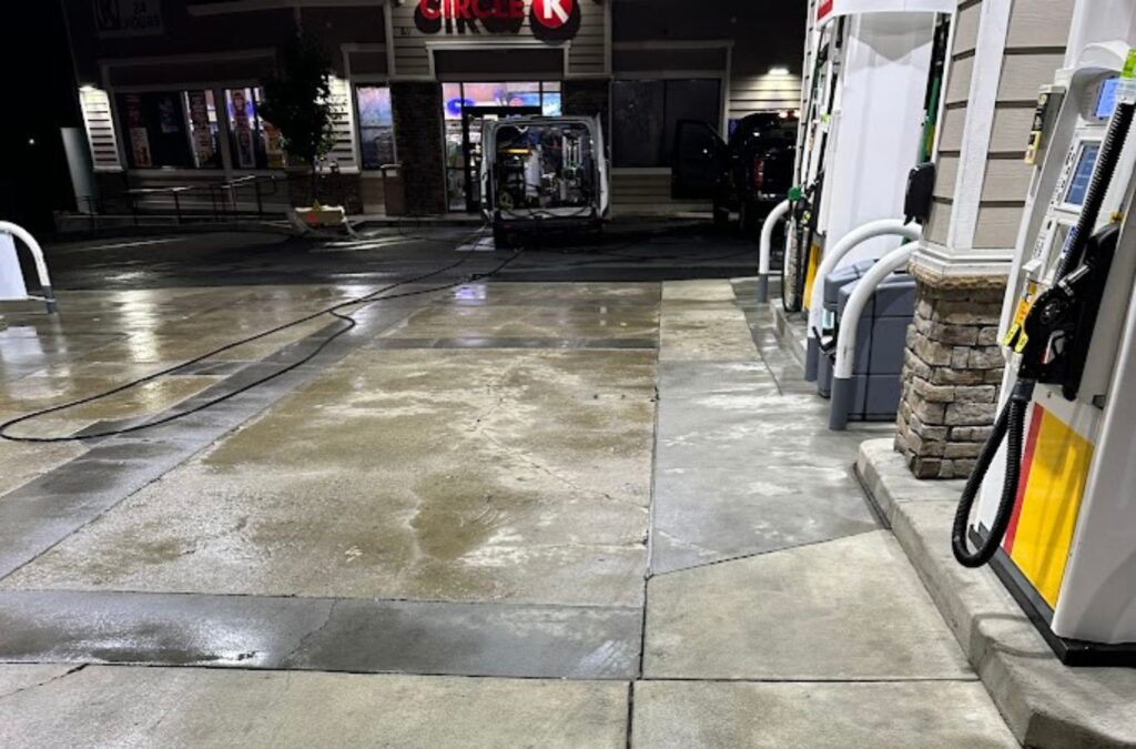 A Slon Exterior Care team member cleaning under fuel pumps in Fremont, CA, showing how proper maintenance improves appearance and customer safety.