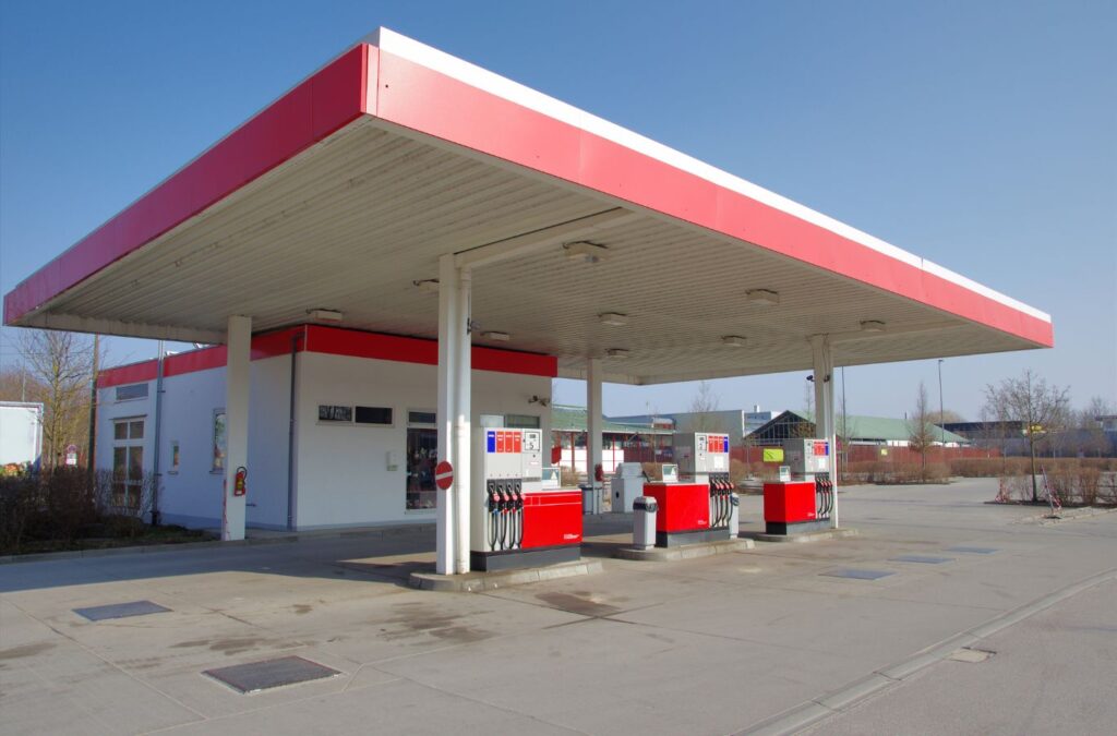 A Slon Exterior Care employee power washing a gas station forecourt in Fremont, CA, removing oil stains and surface debris with professional-grade tools.