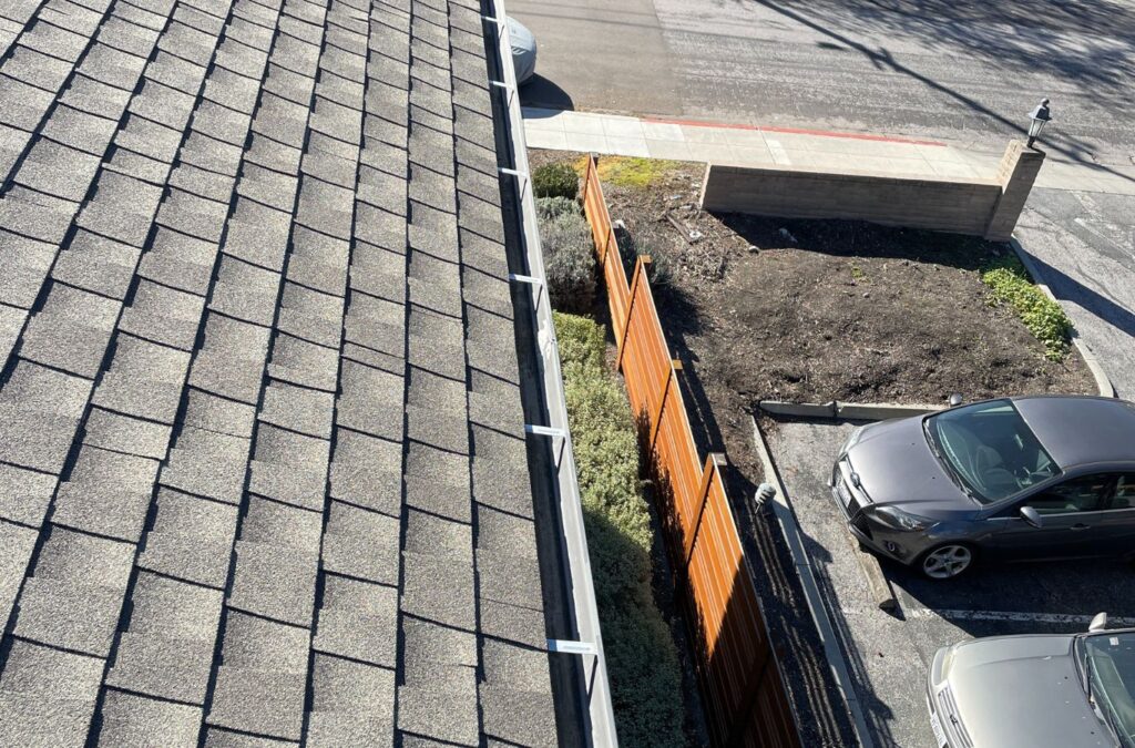 A Slon Exterior Care team member cleaning gutters in Saratoga, CA, highlighting the value of professional service for preventing damage and maintaining flow.